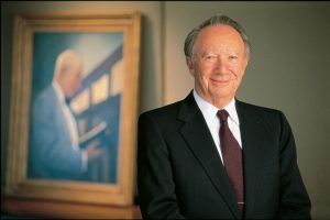 Willard Hackerman, shown in 1998 standing before a portrait of his mentor that hangs behind his office desk, has been a trusted adviser to deans and presidents and a volunteer leader at Johns Hopkins University for more than 70 years.  Along with his wife, Lillian, he has provided philanthropic support on the Homewood campus and at the School of Medicine, notably making the visionary gift that established the Hackerman Scholars, a program providing tuition support for students from Baltimore Polytechnic Institute to attend the Whiting School. He was honored this fall for his unwavering support to the university by the naming of Hackerman Hall on the Homewood campus. Photo: Michael Melford